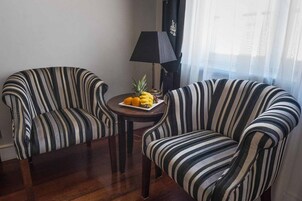 A room with two striped armchairs and a small table with fruit.