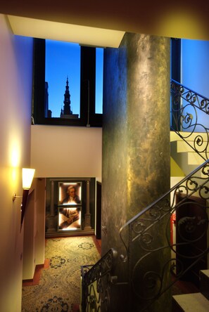 A staircase with ornate metal railings, a patterned carpet, and a view of a cityscape through a window.