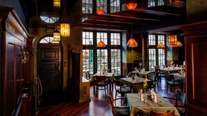 Een restaurant met meerdere eettafels, grote ramen en hangende lantaarns.