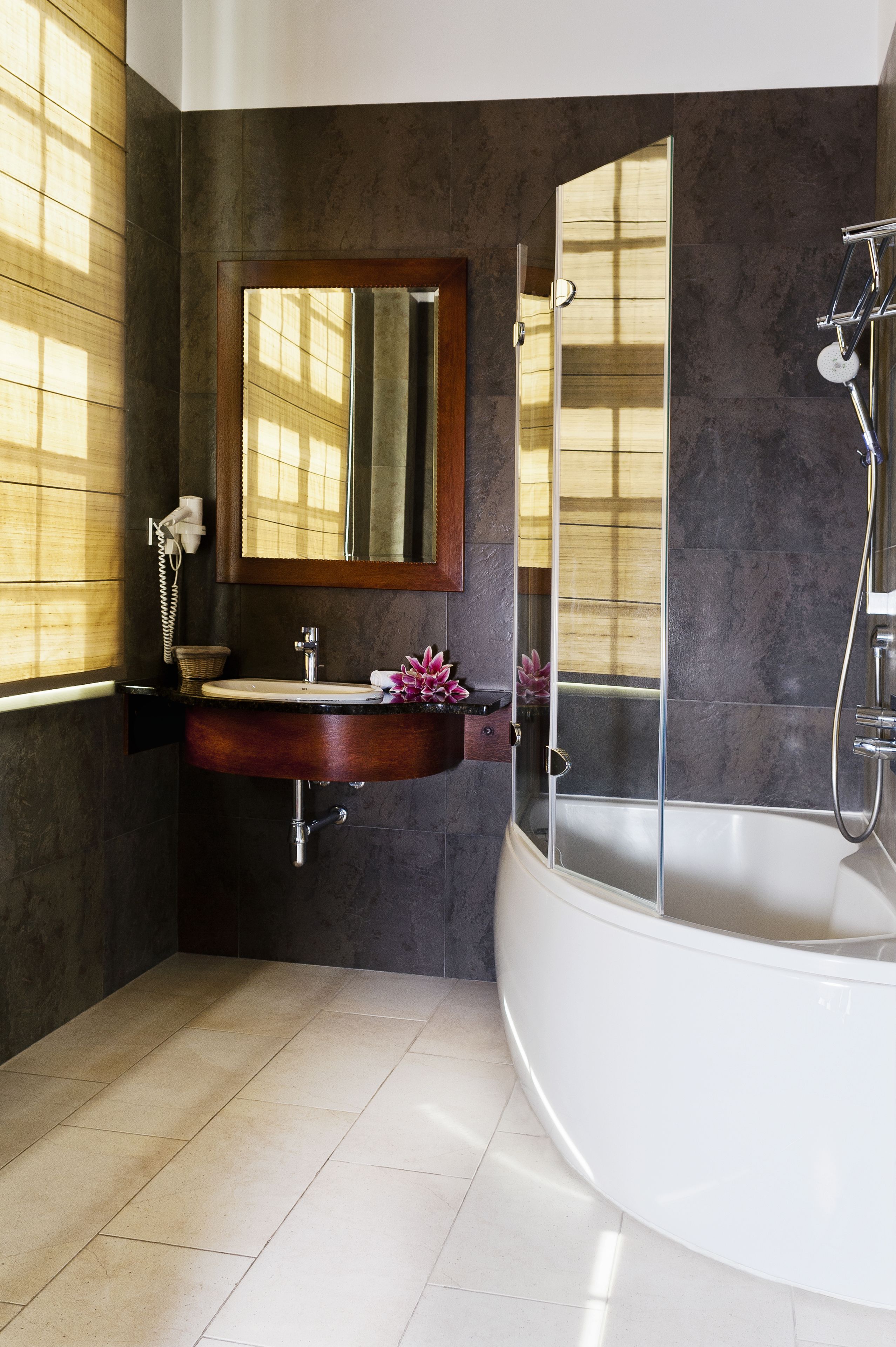 Un baño con una bañera independiente, un lavamanos con espejo y una ventana con persianas.