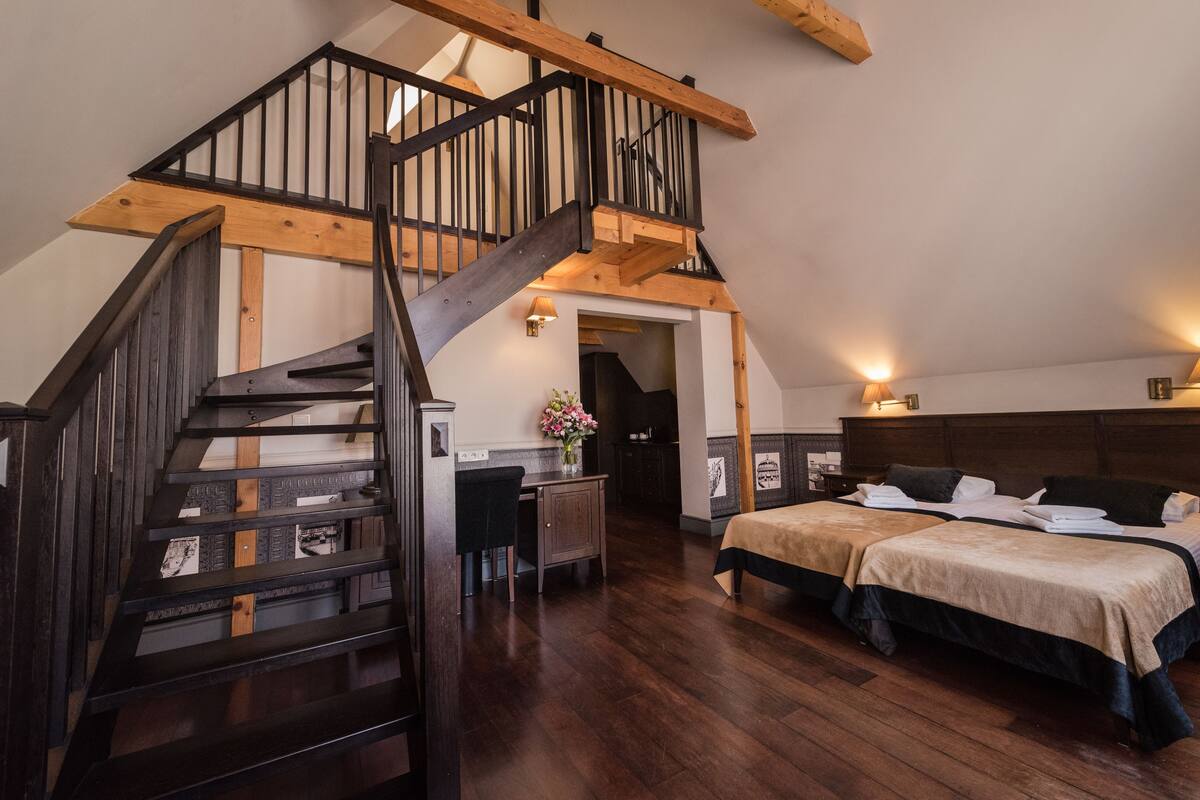 Un dormitorio con escalera de madera, dos camas, un escritorio y una silla.
