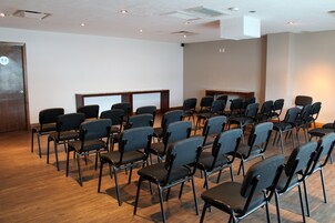 Une salle de conférence avec des rangées de chaises et un pupitre.