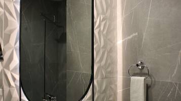 Un baño con un lavamanos rectangular, un espejo grande y un perchero para toallas.