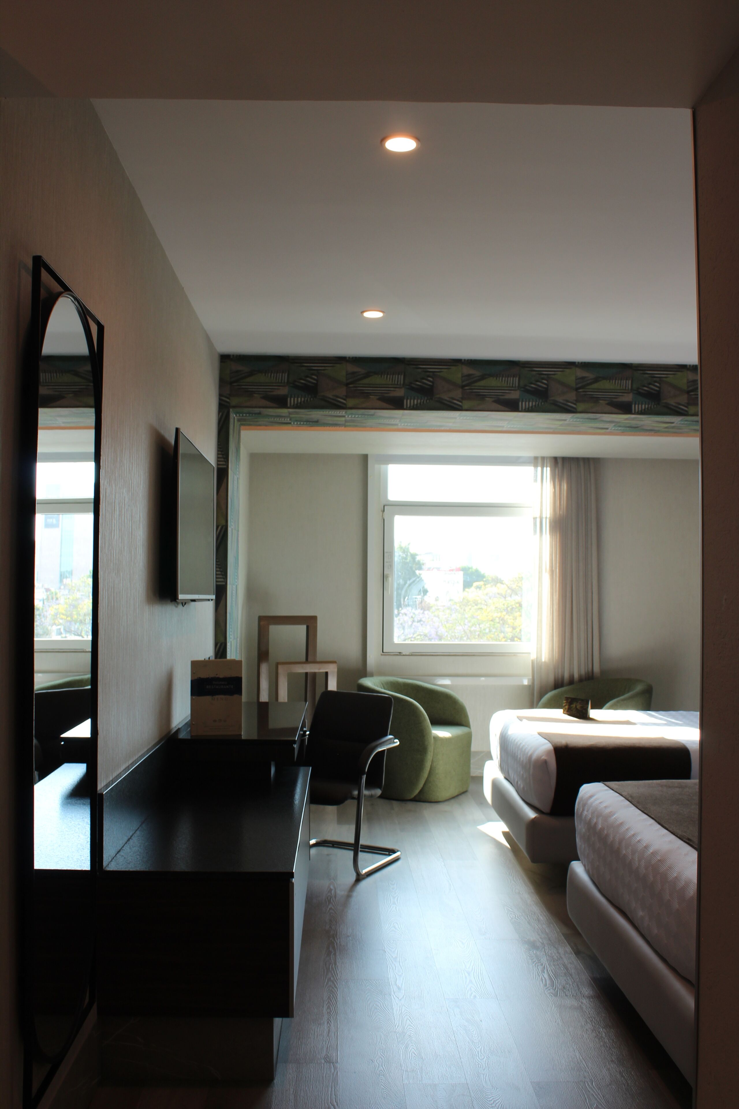 Ein Hotelzimmer mit Bett, Schreibtisch, Stuhl, Spiegel und einem Fenster mit Blick.