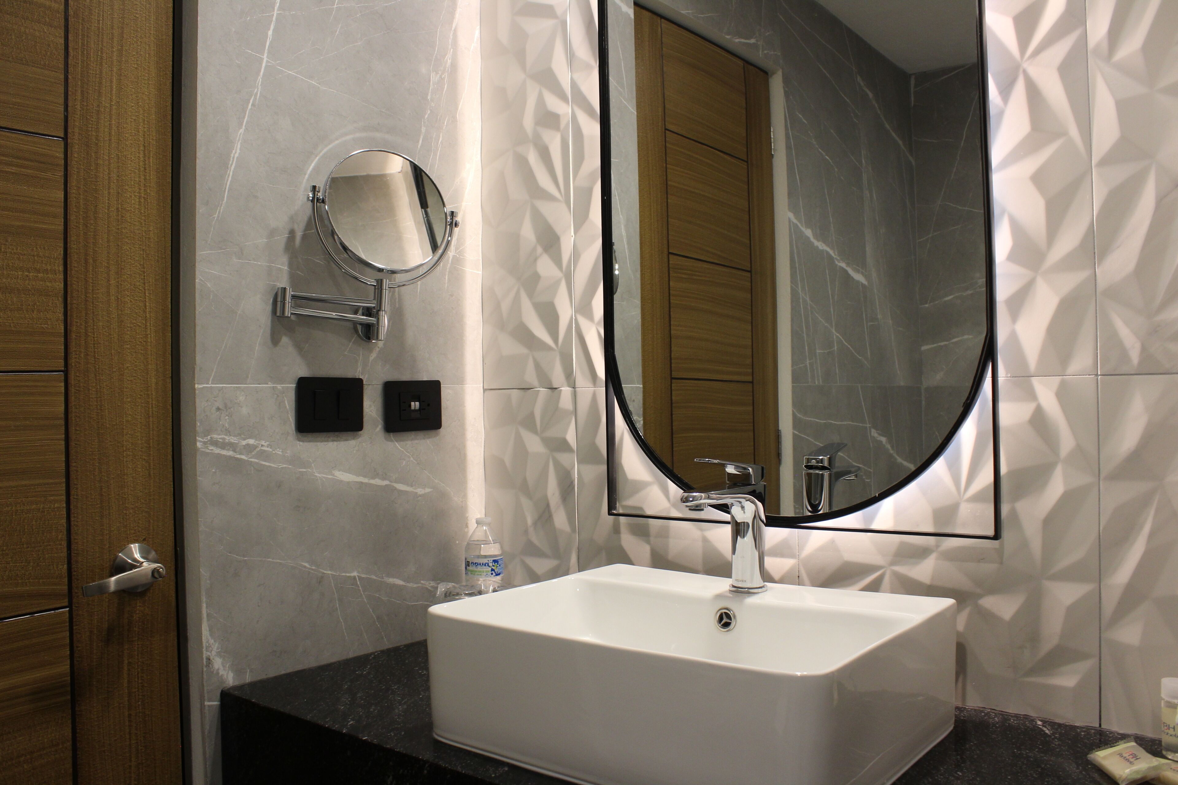 A bathroom with a white sink, a round mirror, and a large mirror above the sink.