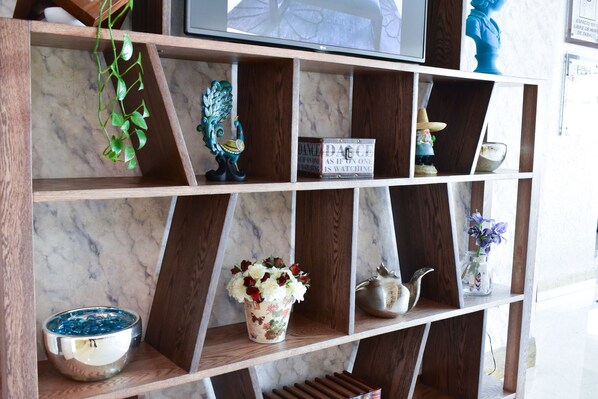 Uma prateleira de madeira com vários objetos decorativos, incluindo um vaso com flores, uma pequena estatueta e uma tigela decorativa.