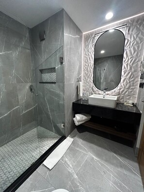 A modern bathroom with a glass shower enclosure, a large mirror, and a black countertop with a sink. - Hotel Portobelo (Guadalajara)