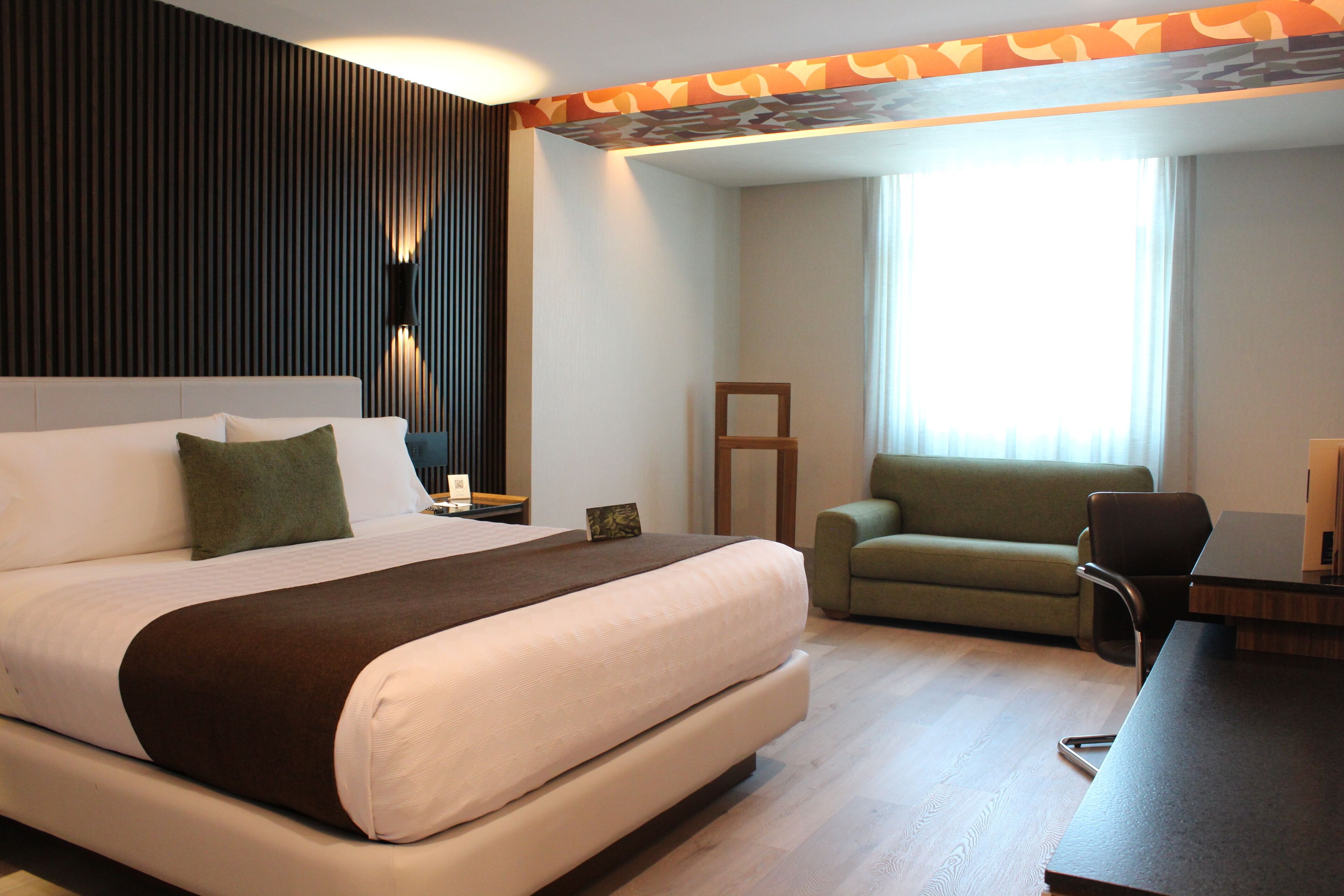 Habitación de hotel con una cama grande, un sofá, un escritorio y una ventana con cortinas.