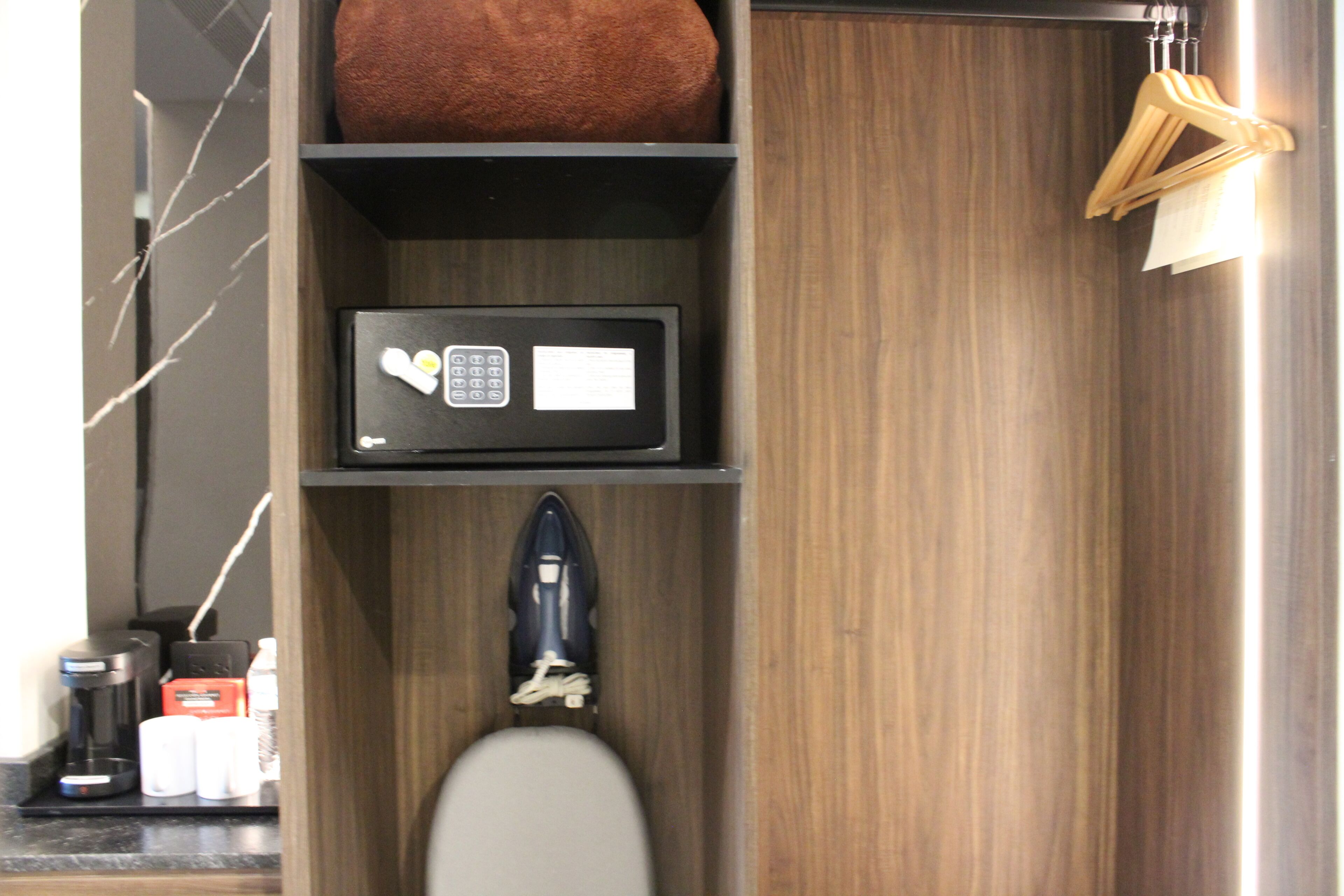 A bathroom with a toilet, a shelf with a microwave, a bottle of hand soap, and a towel rack.