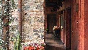 A stone corridor with a wooden ceiling, potted plants, and a star decoration. - Hotel Posada del Angel (Antigua Guatemala)