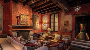 A cozy living room with a fireplace, comfortable seating, and a staircase leading to an upper level. - Hotel Posada del Angel (Antigua Guatemala)