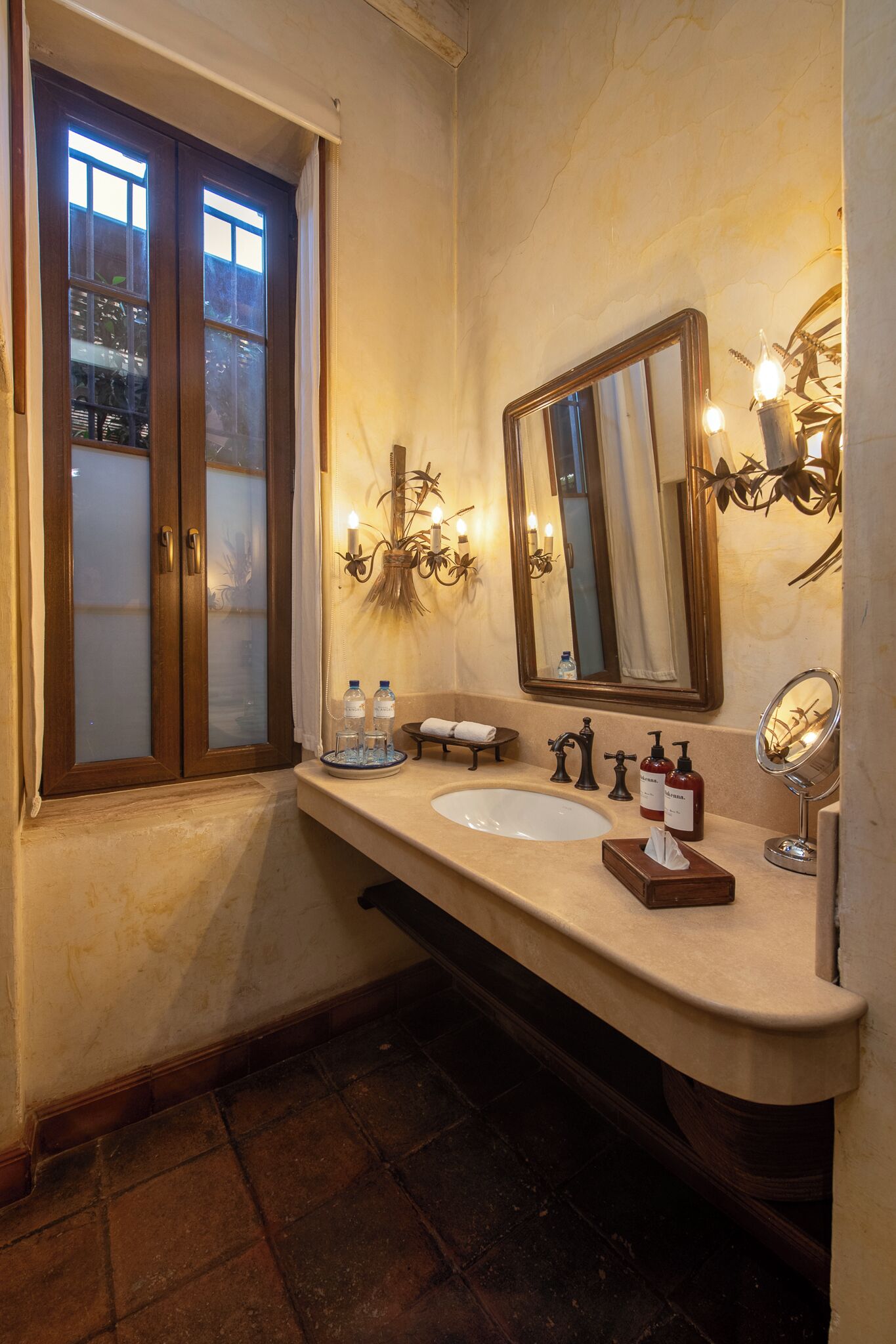 Un baño con un espejo grande, dos lavamanos y una ventana con puertas de vidrio esmerilado.
