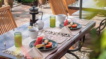Una mesa al aire libre con una cafetera, tazas y un plato de comida.