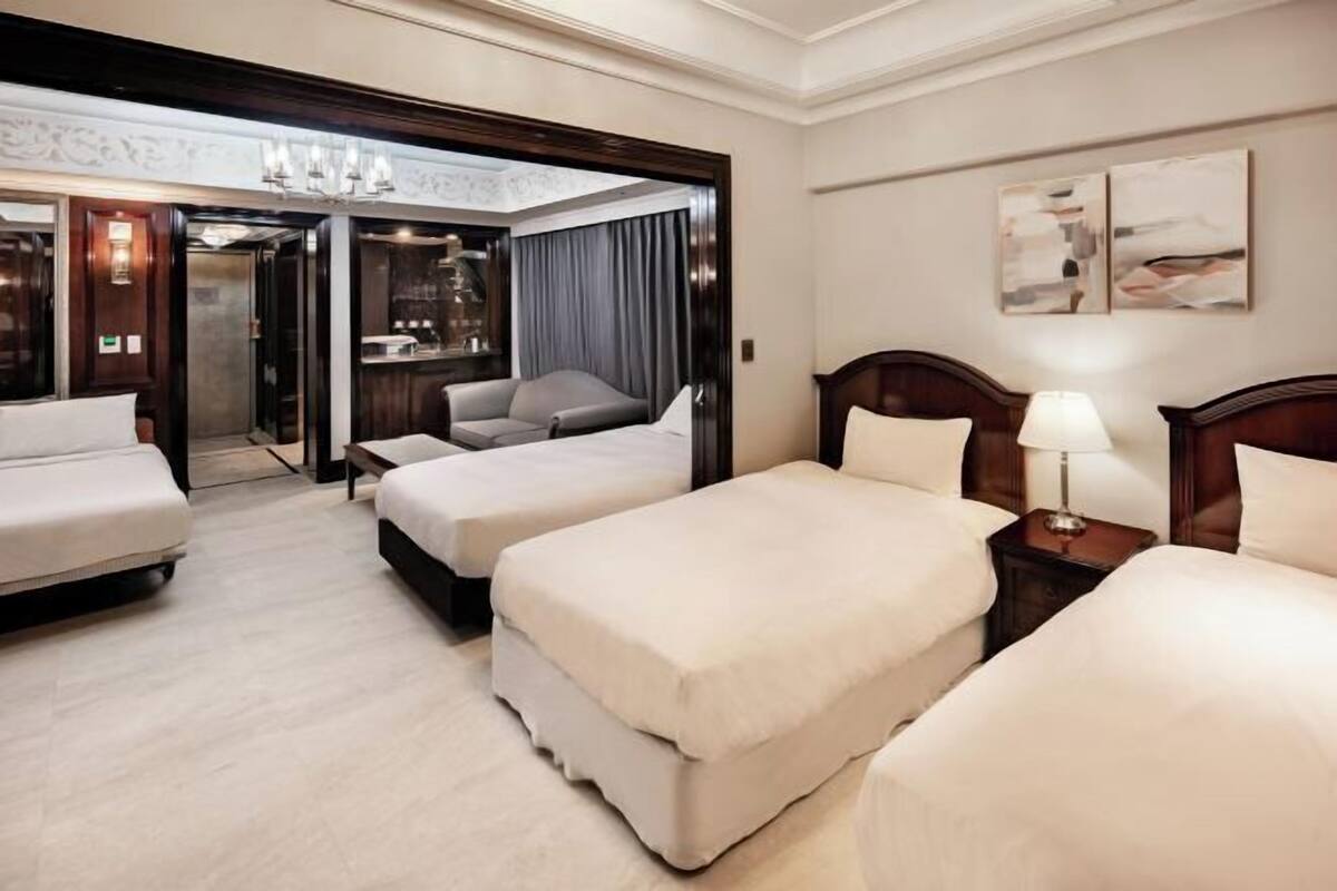 Ein Hotelzimmer mit zwei Betten, einem Schlafsofa, einem Schreibtisch und einer Chandelier.