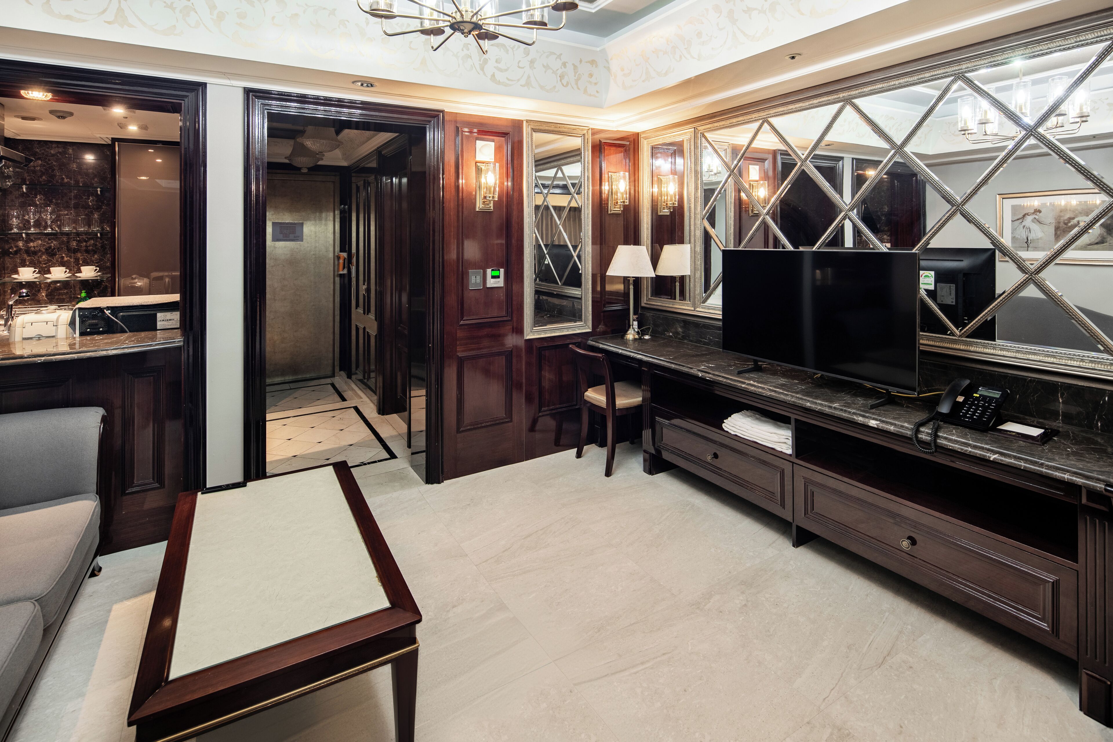 Habitación de hotel con un espejo grande, un escritorio, una silla, un televisor y un minibar.