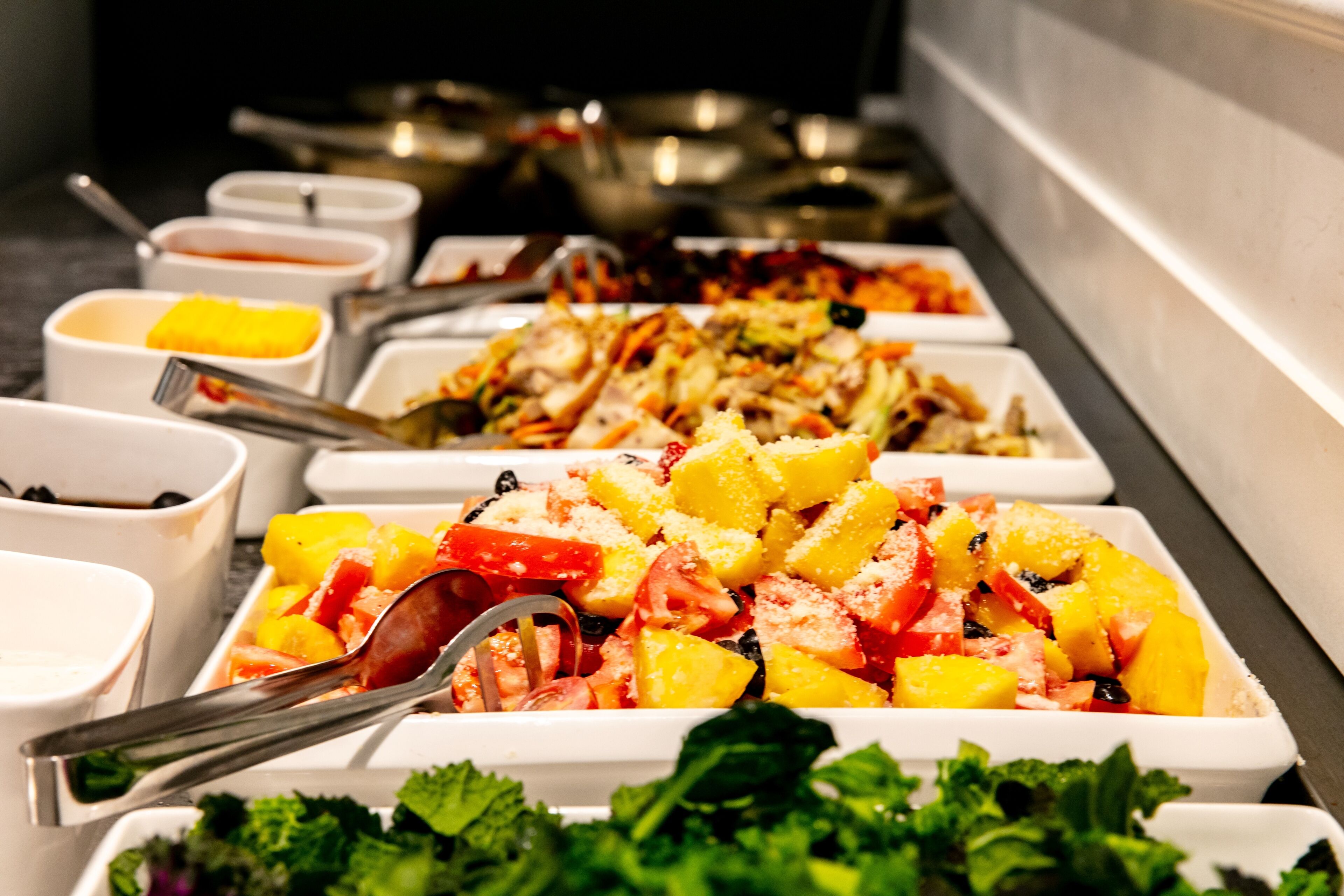 Buffet amb diferents plats, incloent una amanida de fruita, un plat de verdura i un plat de carn.