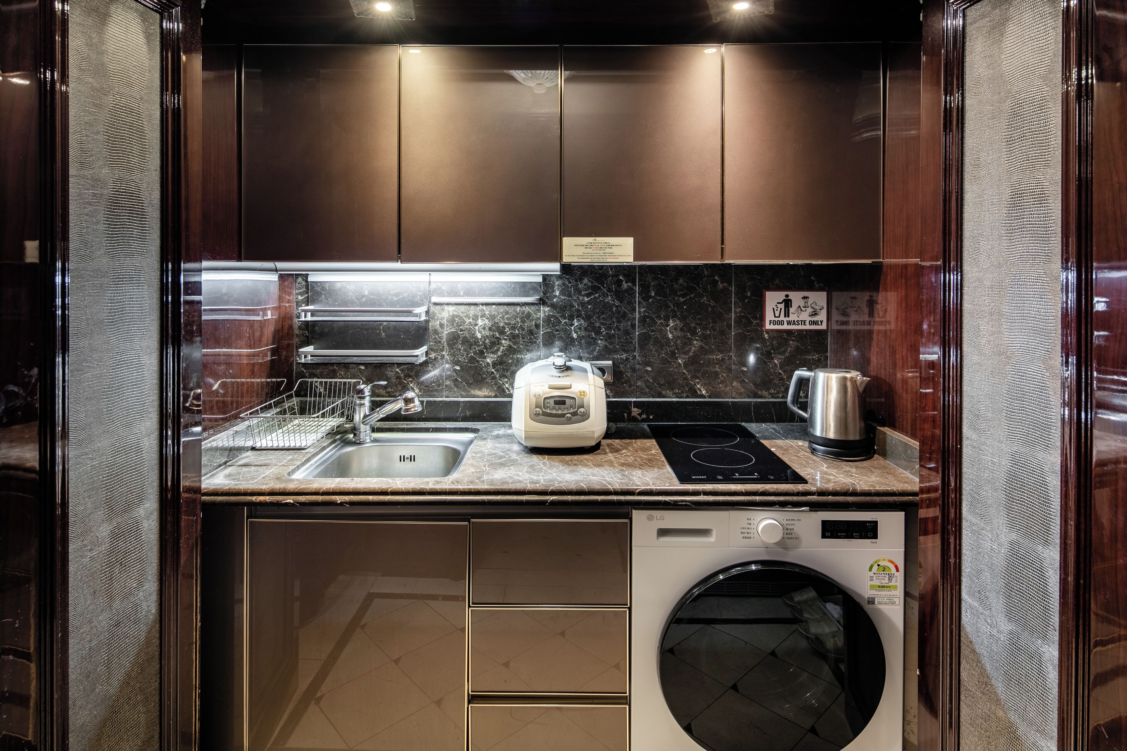 A compact kitchen with a sink, toaster, kettle, and washing machine.