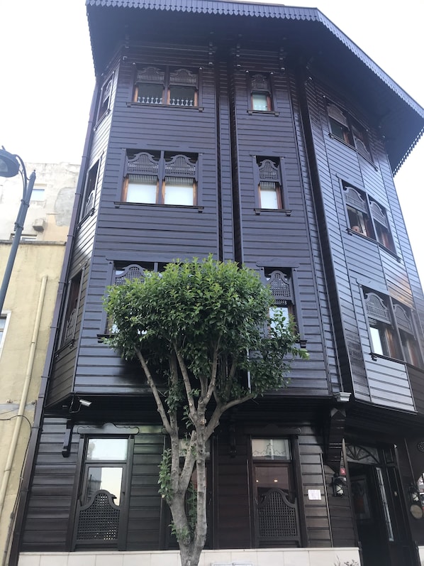 A multi-story building with traditional architectural features, including decorative windows and a tree in front.