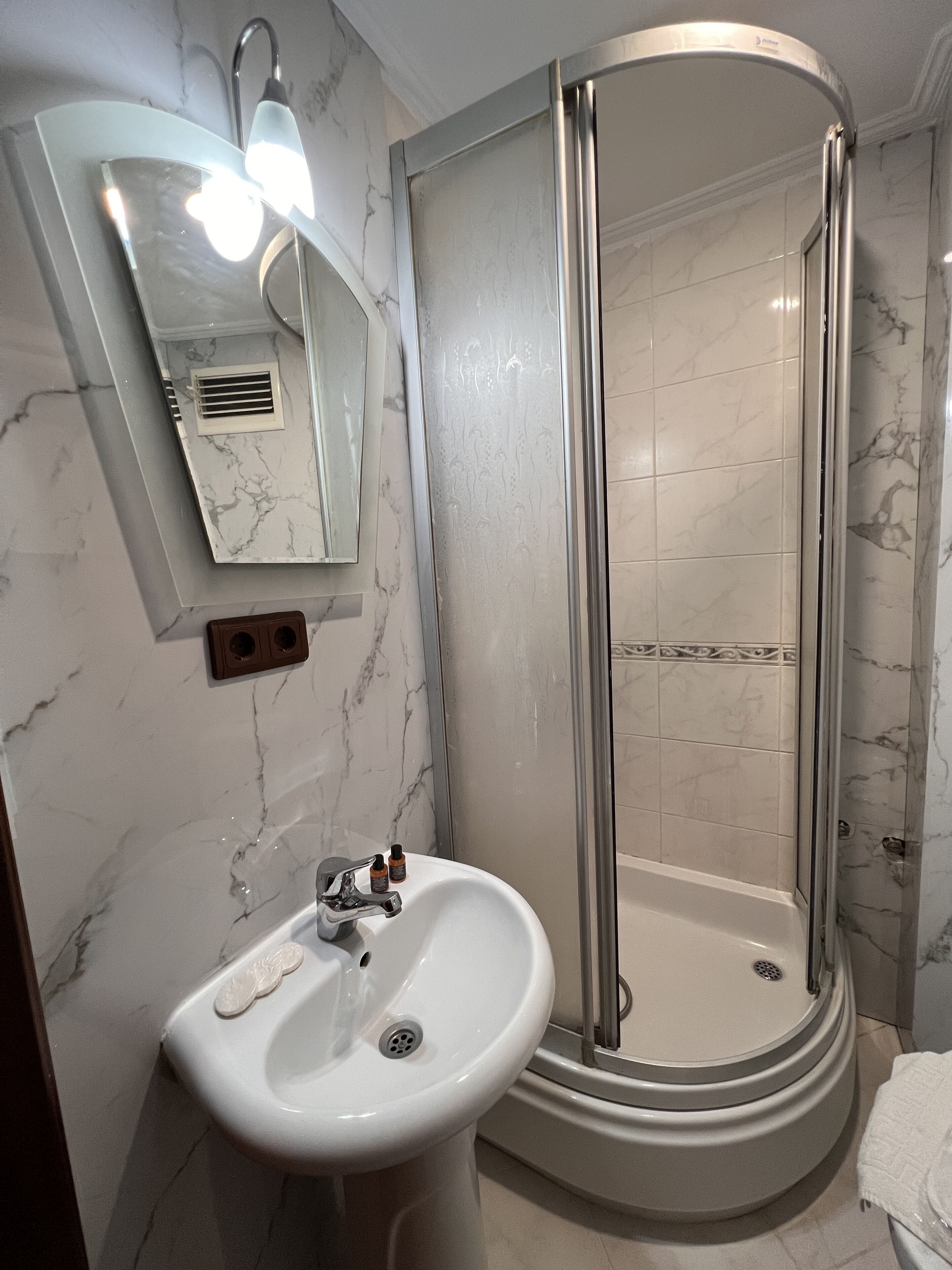 A bathroom with a white sink, a mirror, and a glass-enclosed shower.