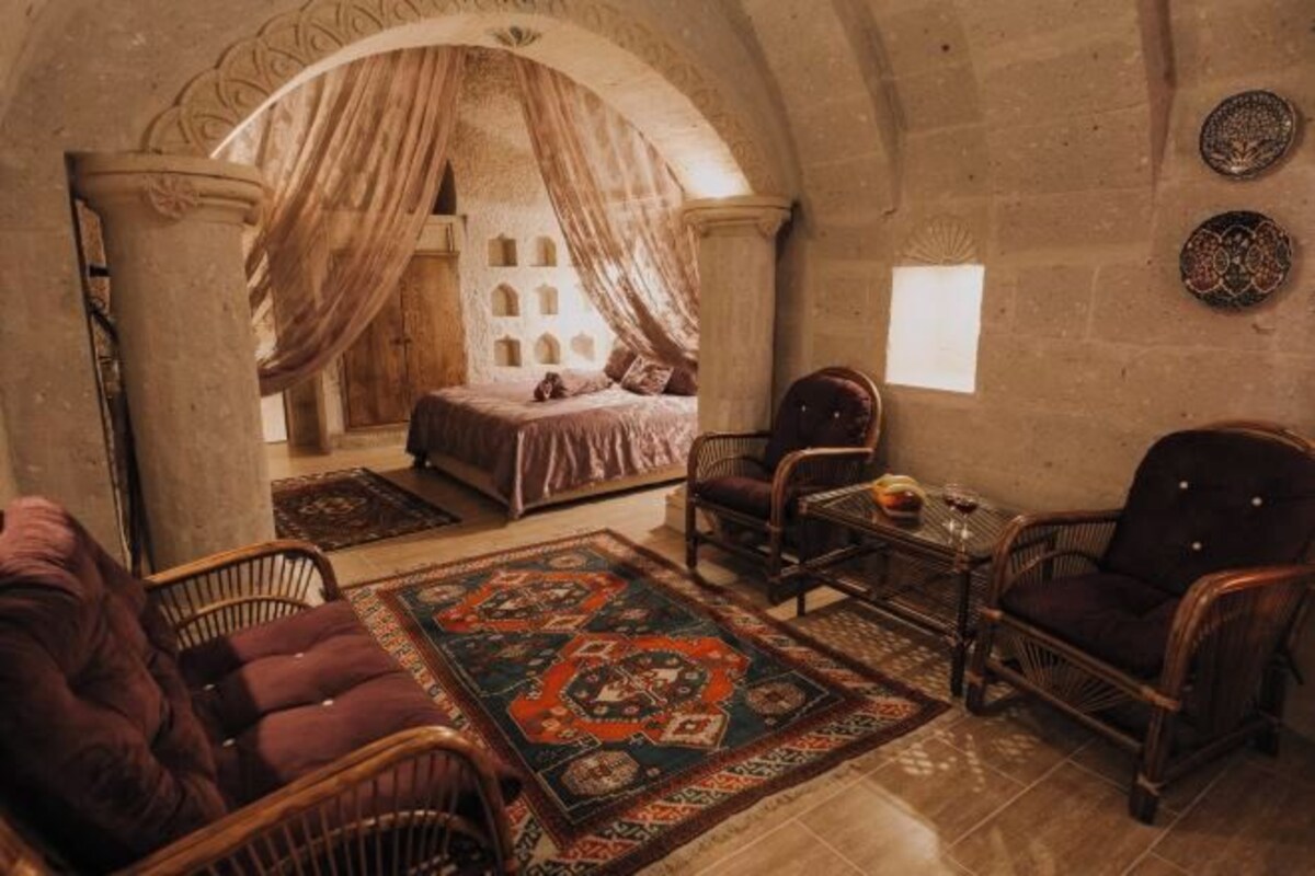 Una habitación con cama, una silla, una mesa y un tapete estampado.