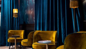 A room with velvet curtains, a standing lamp, and yellow chairs with a small table. - Palazzina Fortuny (Venice)