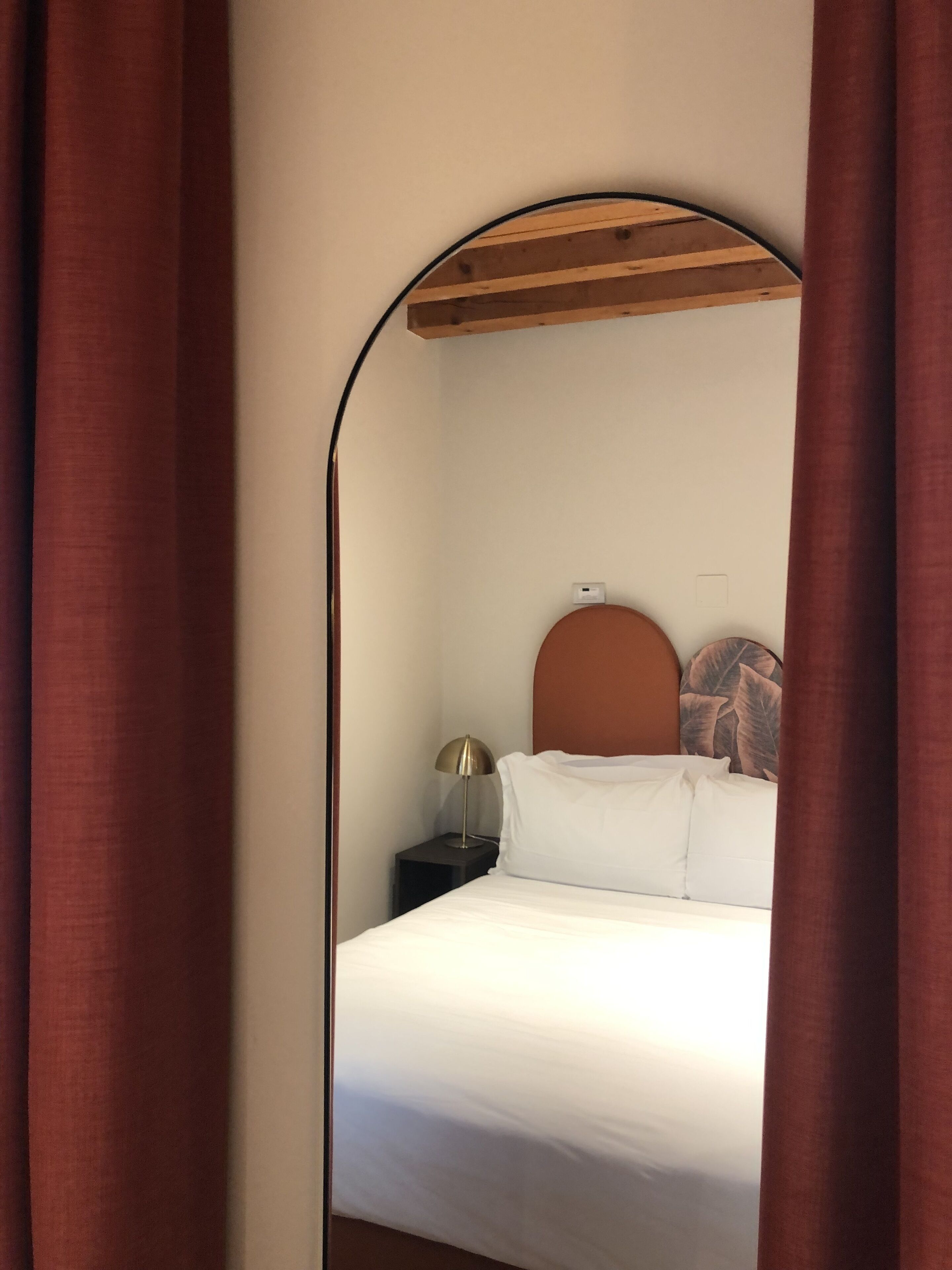 A bedroom with a bed, a nightstand, a lamp, and a wall-mounted shelf.