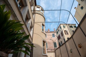 A narrow street with buildings, a plant, and a clear sky. - Palazzina Fortuny (Venice)