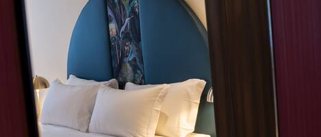 A neatly made bed with white linens and a blue headboard.