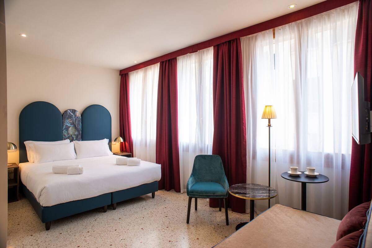 Habitación de hotel con una cama grande, una silla, una mesita y un televisor.
