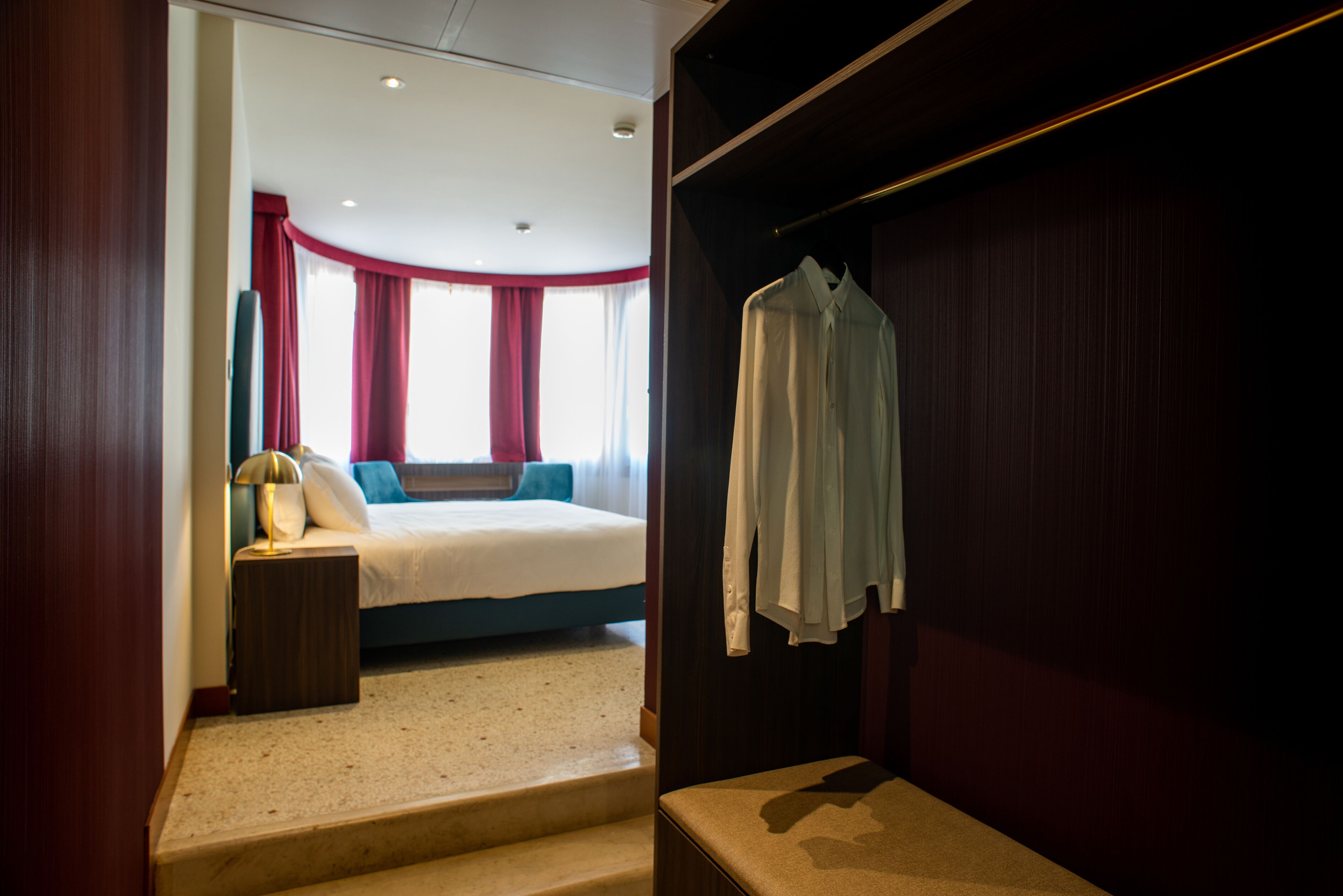 Una habitación de hotel con cama, mesita de noche, espejo y armario.