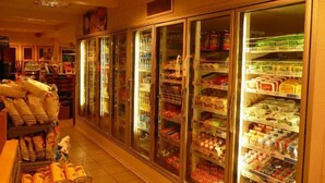 A grocery store with refrigerated sections and shelves stocked with various products.