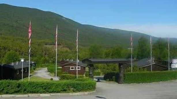 A mountain landscape with a small building and a covered area, likely a lodge or cabin.