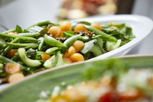 Primer plano de una ensalada con verduras verdes y garbanzos.