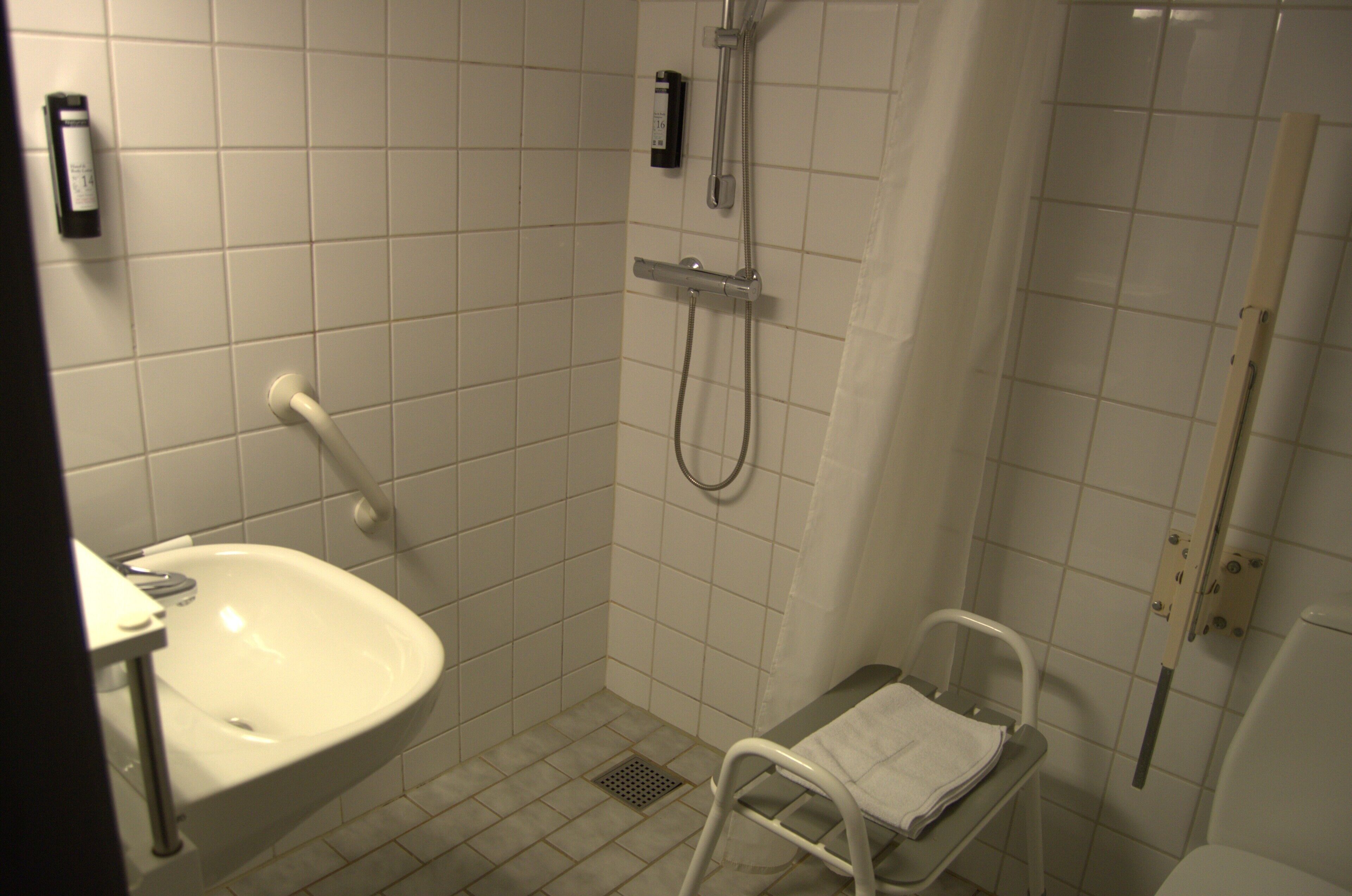 Un bagno piccolo rivestito di piastrelle, con lavandino, doccia e WC.