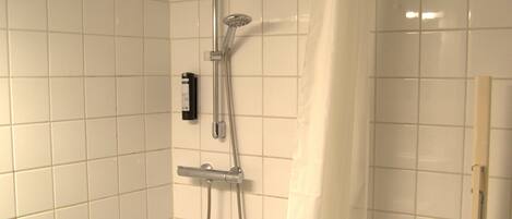 A small, tiled bathroom with a shower, a toilet, and a sink.