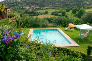 Relax by the serene pool surrounded by lush greenery and vibrant flowers.