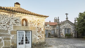 Un edificio de piedra con techo de tejas y una cruz en la parte superior, lo que sugiere un lugar religioso o histórico.