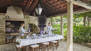 Un área de comedor al aire libre con chimenea de piedra, mesa y sillas de madera.