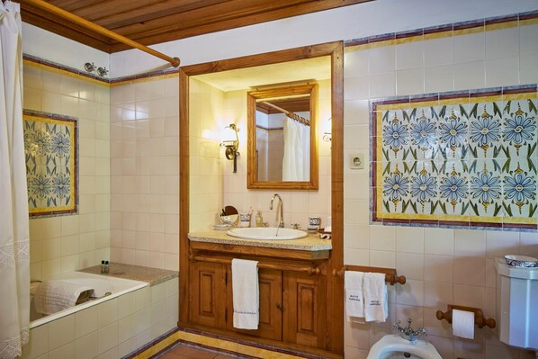 A bathroom with a wooden vanity, a sink, a mirror, a shower, and a toilet.
