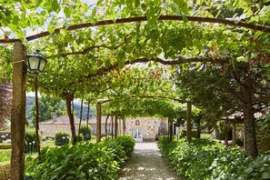 A stone building with a covered walkway surrounded by lush greenery.