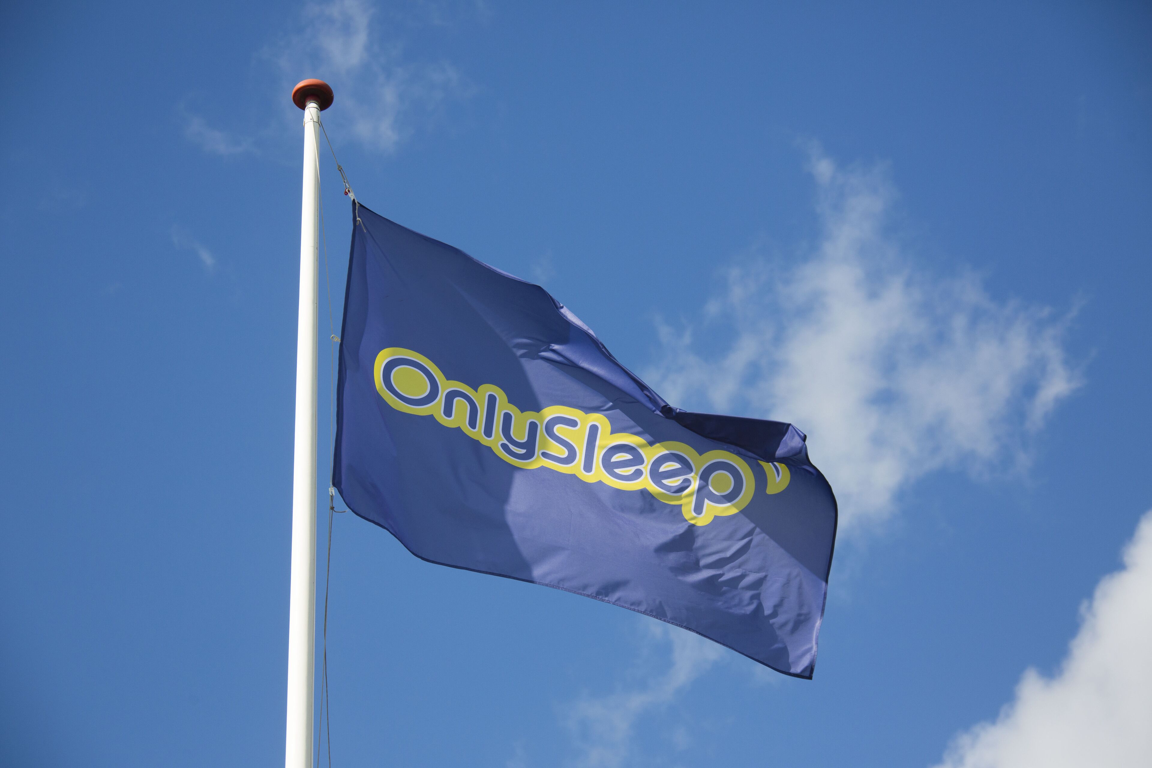 A flag with the text "OnlySleep" on a flagpole against a clear blue sky.