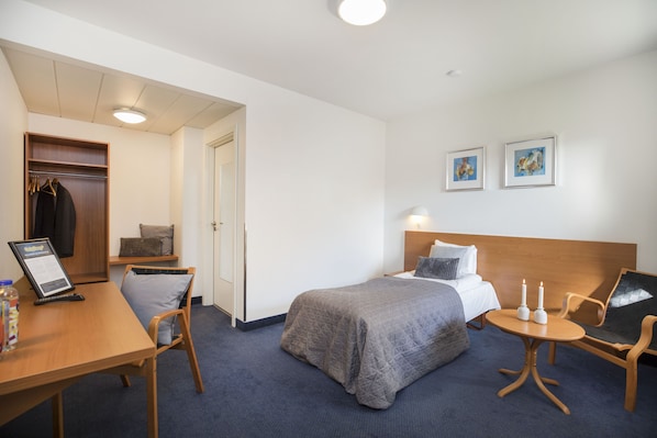 Une chambre d’hôtel comprenant un lit, une table de chevet, une chaise, un bureau et une armoire.