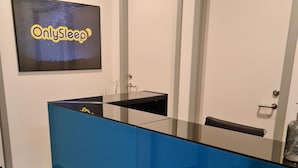A reception desk with a blue counter, a framed sign above it, and two doors in the background.