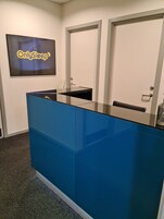 Um balcão de recepção azul, um letreiro emoldurado acima e duas portas ao fundo.
