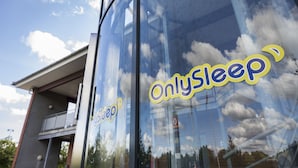 A building with a glass facade reflecting clouds and sky. The text "OnlySleep" is visible on the glass.