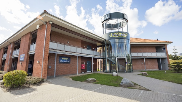 A hotel with a reception area, a glass elevator, and a brick facade.