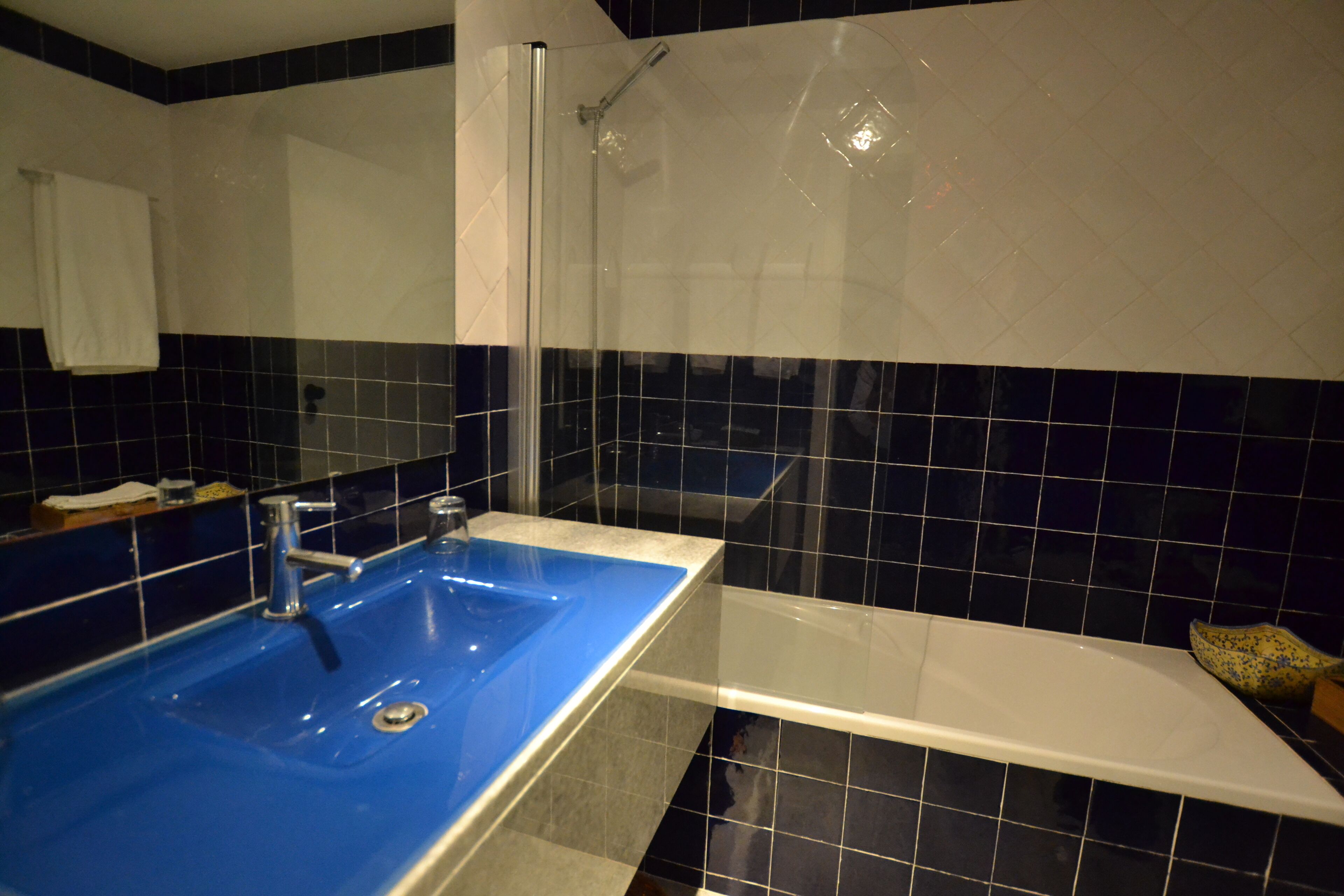 A bathroom with a blue sink, a white bathtub, and a glass shower enclosure.