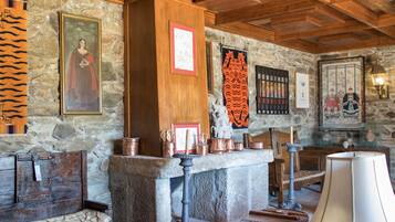 A rustic interior with stone walls, wooden beams, a stone fireplace, and traditional decor.