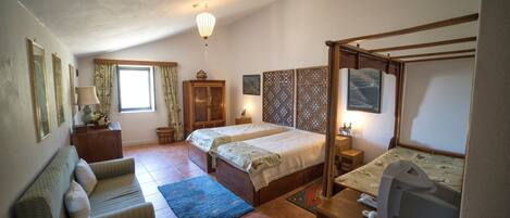A bedroom with two beds, a sofa, a desk, and a TV.