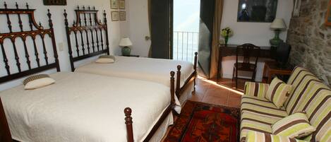 Un dormitorio con dos camas, un sofá, un escritorio y vistas al exterior.